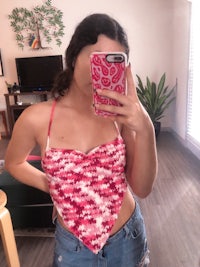 a woman taking a selfie in a pink crochet top