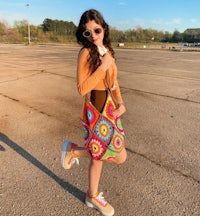 a young woman wearing a crocheted bag and sunglasses