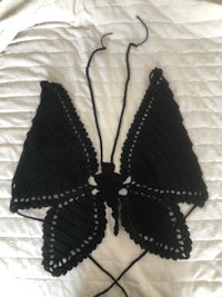 a black crocheted butterfly bikini top on a bed