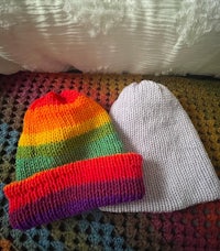 two knitted beanie hats on a bed