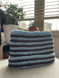 a blue and brown crocheted bag sitting on a table