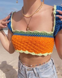 a woman wearing a crocheted top on the beach