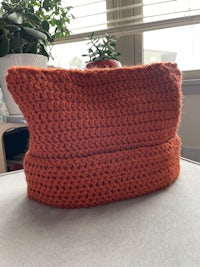 an orange crocheted beanie sitting on top of a table