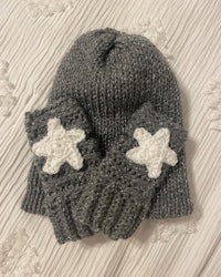 a pair of grey knitted mittens with white stars on them