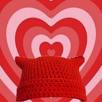 a red crocheted hat in front of a heart shaped background