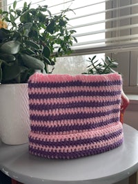 a pink and purple crocheted basket sitting on a table